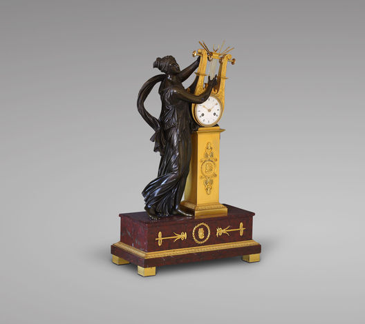 Галерея Jacques Neve. Каминные часы с изображением Эрато, ок. 1805 год. Каррарский мрамор, позолоченная и патинированная бронза. Подпись: Manire  Paris.  Маньер стал мастером в 1778 году. Бронза: Пьер-Филип Томир (1751-1843), самый известный автор декоративных предметов из патинированной и позолоченной бронзы в эпоху Первой Французской Империи  В 64 x Ш 38 x Г 19 см